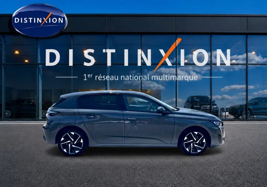 Profil droit de la Peugeot 308 gris 2025 avec jantes alu noires et design moderne devant une vitrine Distinxion.