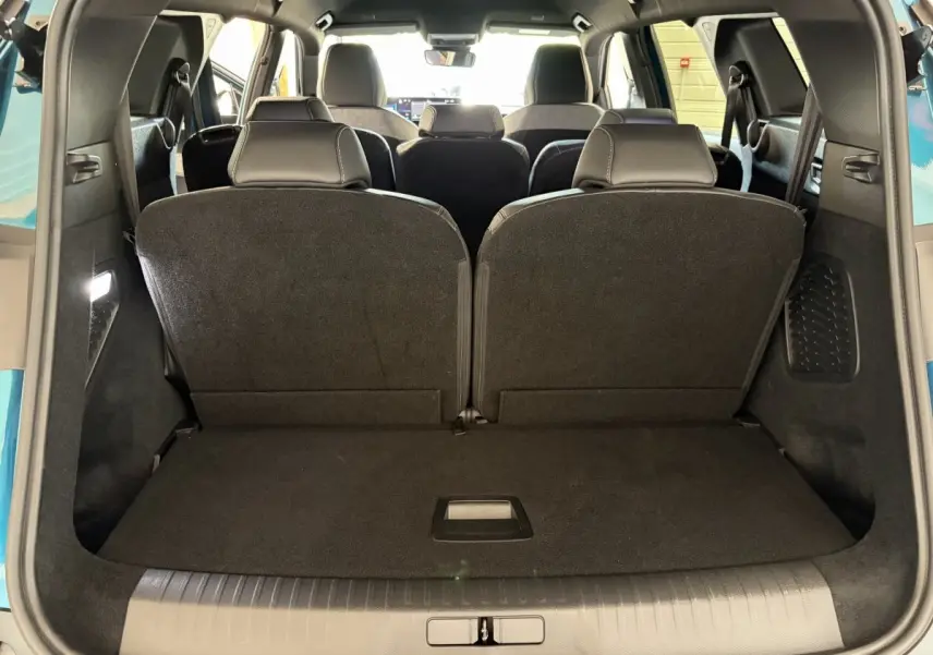 Vue arrière du coffre du Peugeot 5008 hybride vert 2025 avec troisième rangée de sièges rabattus et intérieur noir.