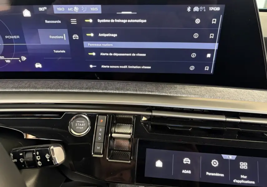 Gros plan sur le tableau de bord du Peugeot 5008 Hybrid 2025 avec écran tactile et commandes de boîte auto.