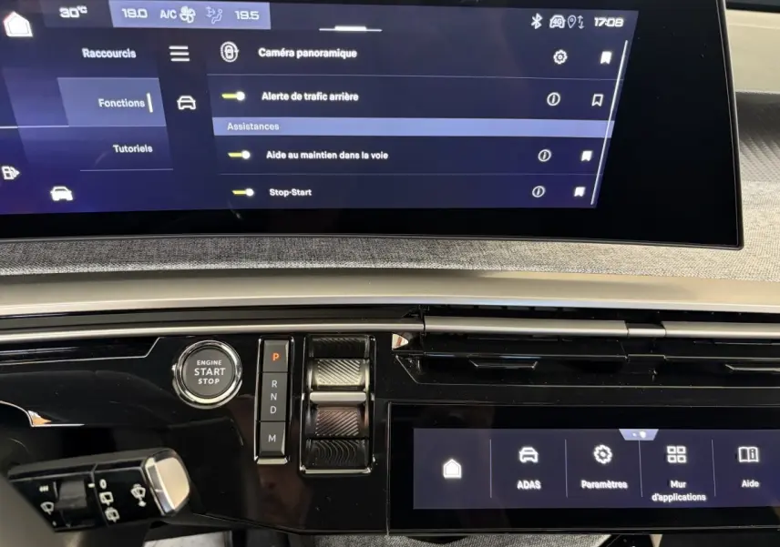 Vue rapprochée du tableau de bord du Peugeot 5008 hybride 2025, écran tactile et commande de démarrage visibles.