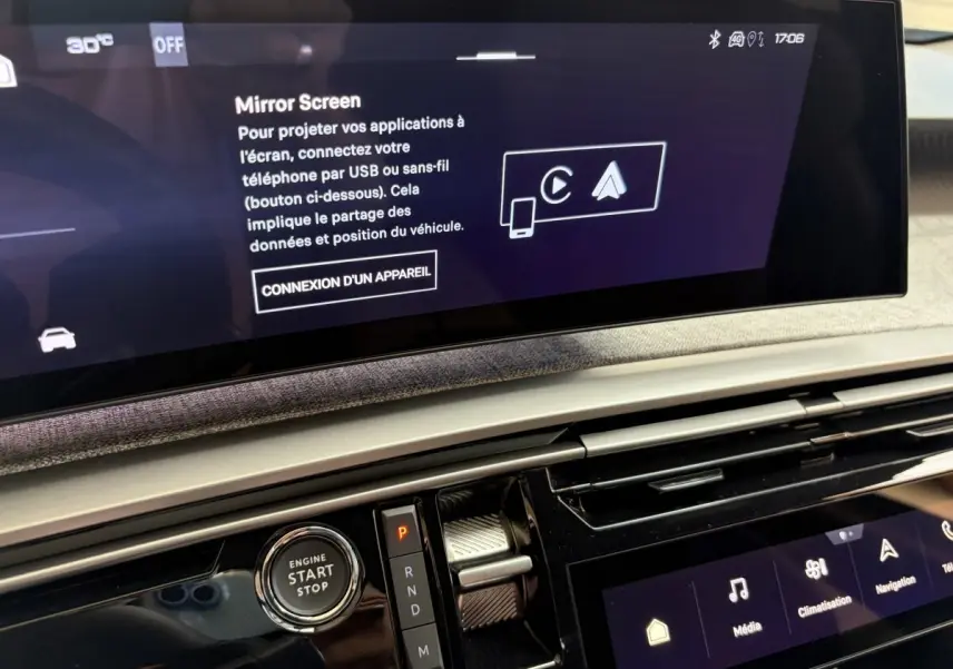 Vue rapprochée de l’écran tactile central et de la commande de démarrage du Peugeot 5008 hybride vert, intérieur moderne et épuré.