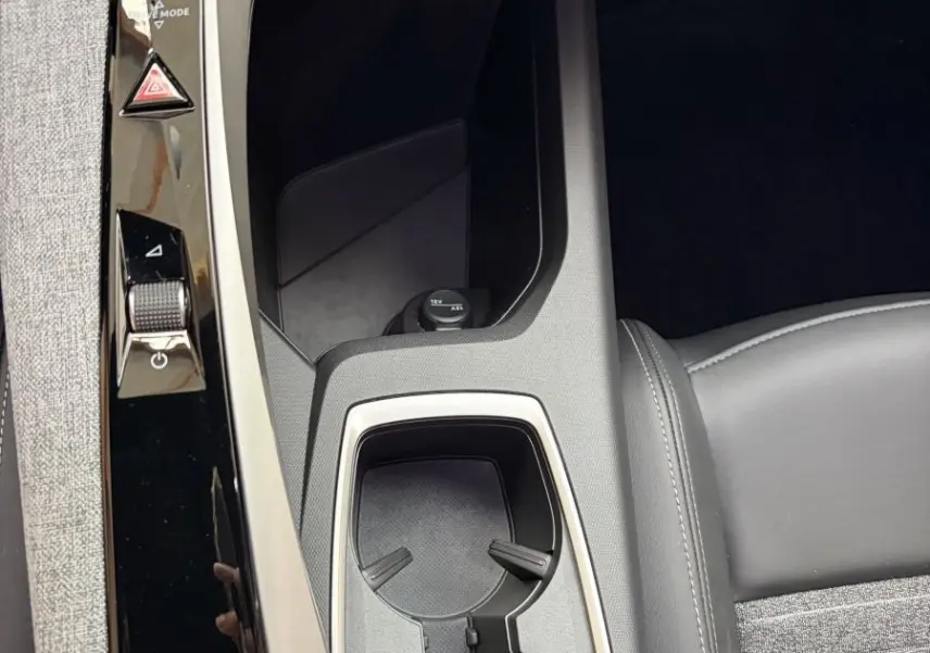 Gros plan sur la console centrale noire et grise du Peugeot 5008 Hybrid avec porte-gobelets et commandes tactiles.
