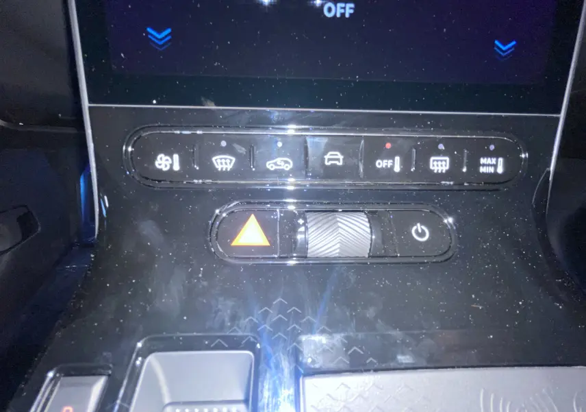 Gros plan sur la console centrale noire du Citroën C5 Aircross hybride, montrant les commandes climatisation et bouton hazard.
