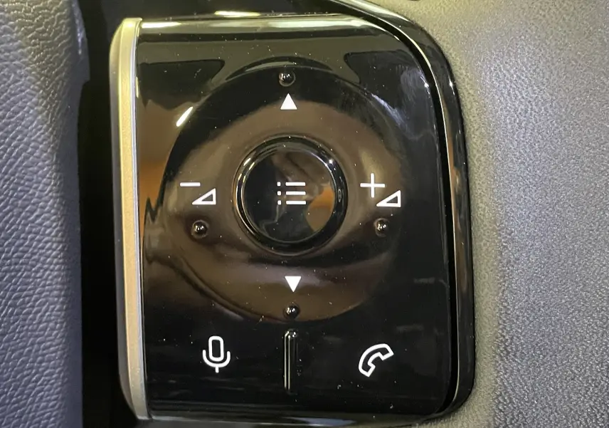 Gros plan sur les commandes au volant noir brillant du Citroën C5 Aircross hybride 2026, boutons volume et appels.