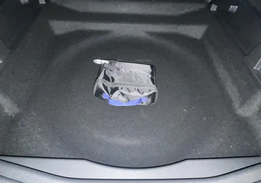 Coffre ouvert d'une Citroën C5 Aircross hybride gris platinium avec toit noir, montrant un sac noir au centre.