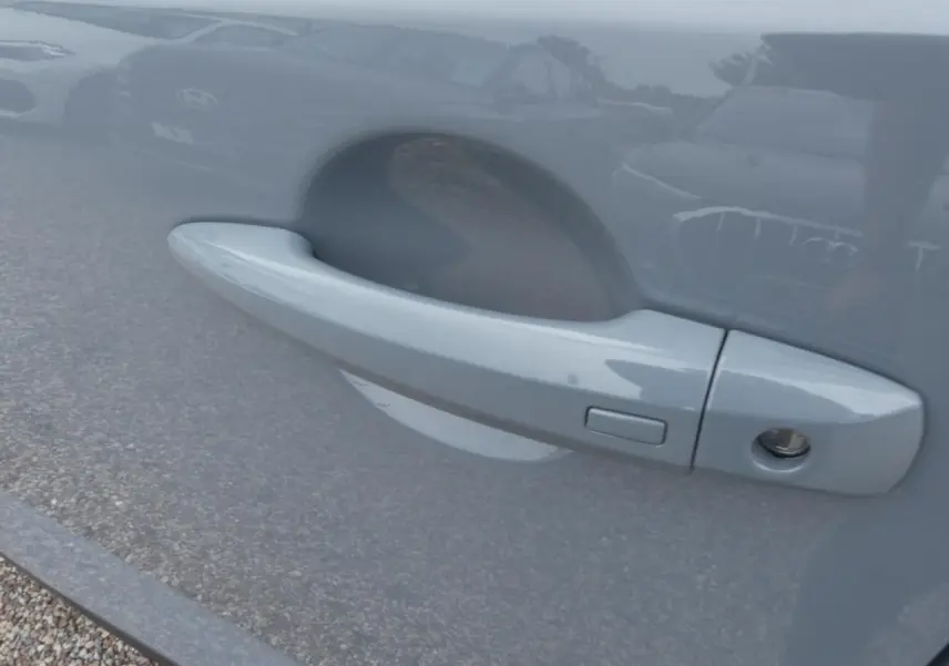 Poignée de porte côté gauche gris métallisé du Nissan Qashqai 1.5 e-Power 2025 avec serrure et bouton d'ouverture.