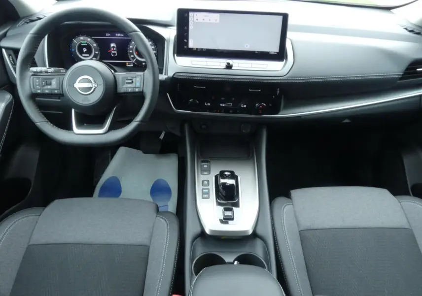 Intérieur du Nissan Qashqai 2025, vue avant centrée sur tableau de bord, console et sièges gris tissu et TEP.