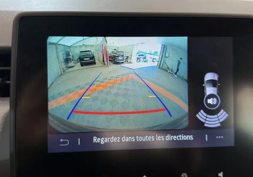 Affichage caméra de recul sur écran tactile d'une Renault Clio noire, avec guidage de trajectoire et capteurs de stationnement actifs.