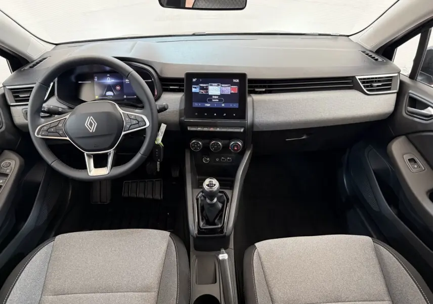 Vue intérieure avant de la Renault Clio 2025 avec tableau de bord gris clair, volant multifonctions et boîte manuelle.