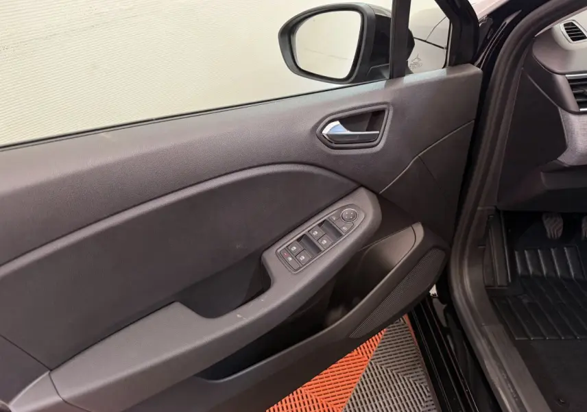 Vue intérieure côté gauche de la porte avant noire d'une Renault Clio 2025 avec commandes électriques des vitres.