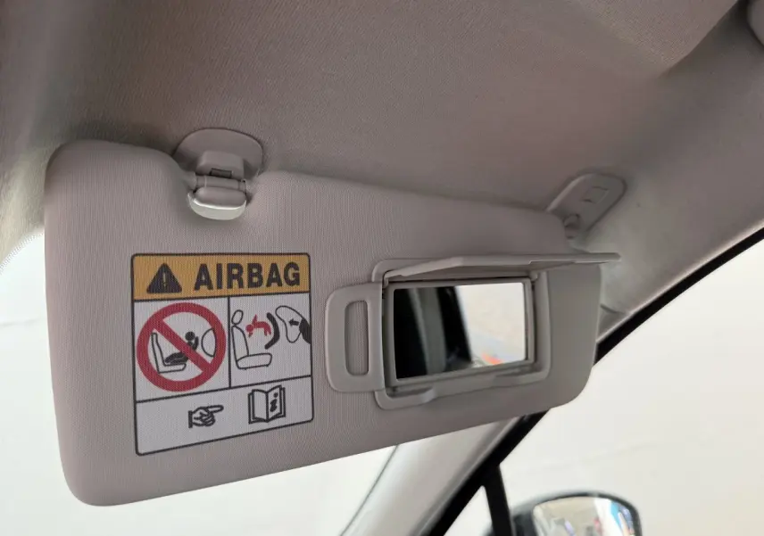Détail du pare-soleil côté conducteur beige avec miroir ouvert et avertissement airbag dans une Renault Clio noire 2025.