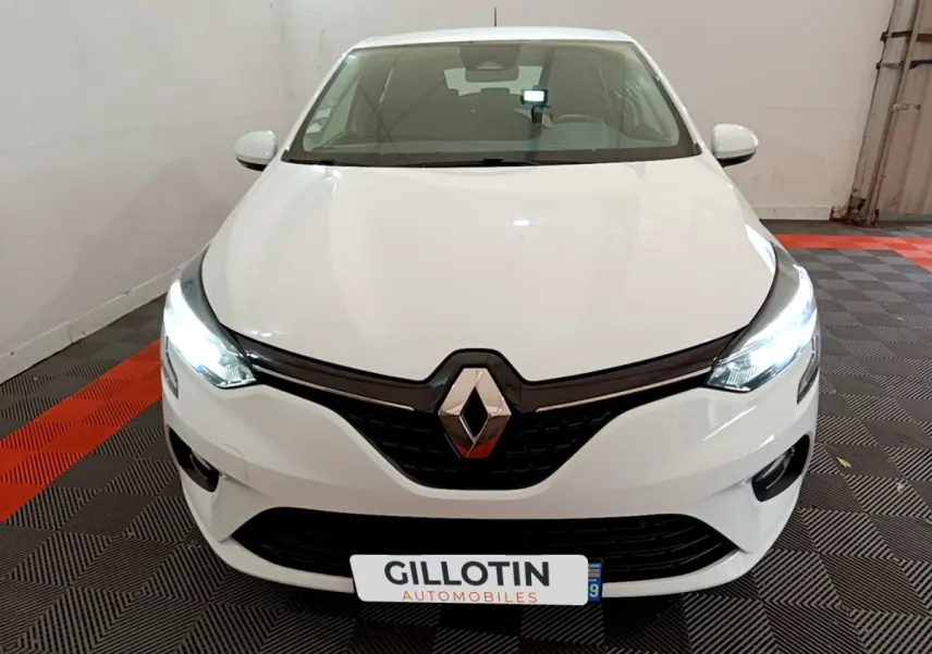 Vue avant d'une Renault Clio Business TCe 100 blanche avec phares LED allumés dans un showroom.