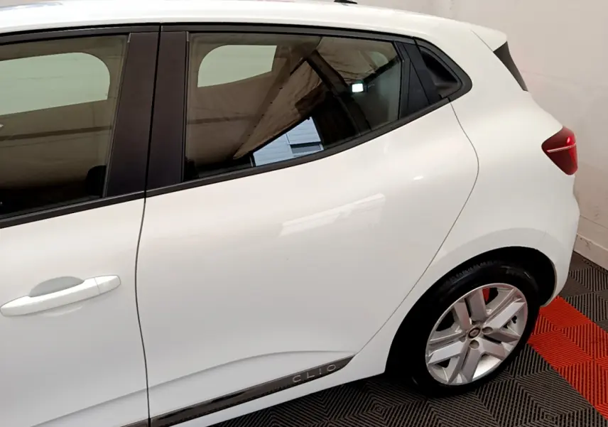 Vue latérale droite rapprochée d'une Renault Clio blanche 2020 avec jantes alliage et poignées de porte intégrées.