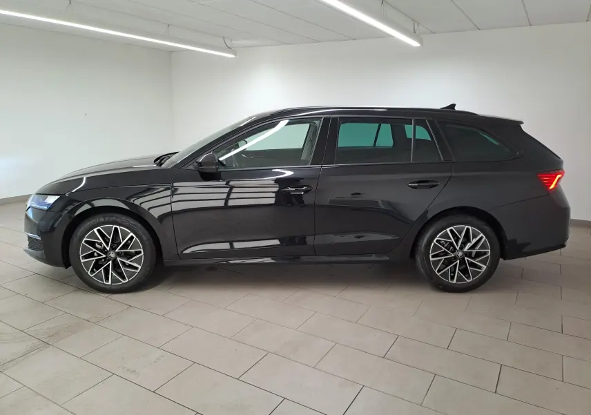 Profil droit d'une Skoda Octavia Combi 2025 noire Magic nacré avec jantes alliage 17'' Slagard Aero noir polies et vitres surteintées.