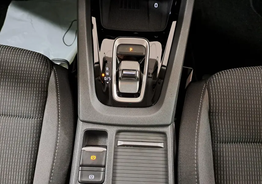 Vue plongeante sur la console centrale de la Skoda Octavia Combi 1.5 TSI 150 DSG7 avec levier de vitesse électronique et sièges tissu noir.