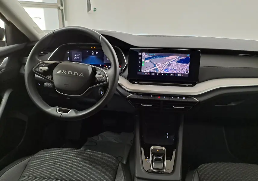 Vue intérieure du poste de conduite de la Skoda Octavia Combi 2025 avec écran tactile central et volant multifonction noir.