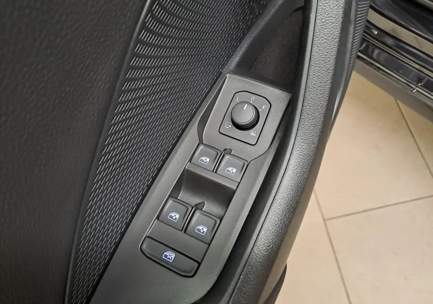 Gros plan sur les commandes de lève-vitres et réglage des rétroviseurs côté conducteur d'une Skoda Octavia Combi noire.