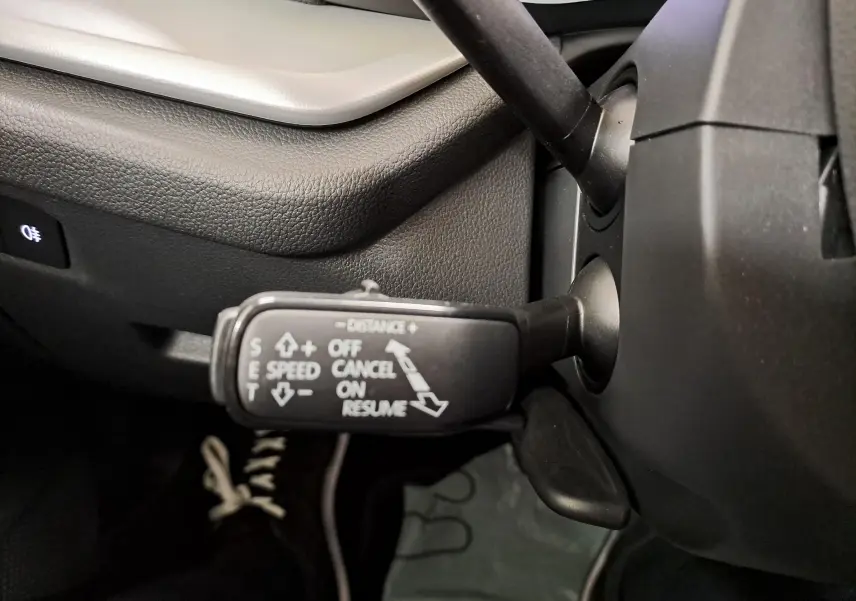 Gros plan sur la commande de régulateur de vitesse à gauche du volant dans une Skoda Octavia Combi noire.