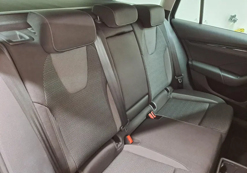 Vue intérieure sur les sièges arrière en tissu noir avec appuie-têtes et ceintures de sécurité visibles.