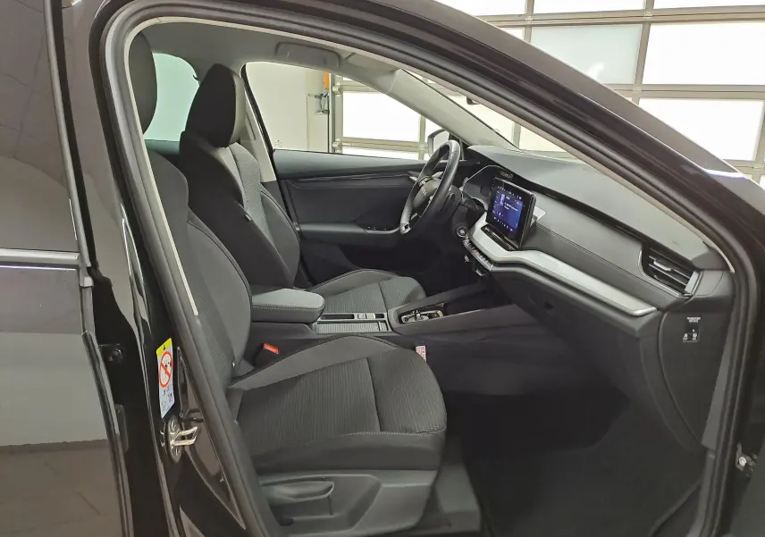 Intérieur avant droit de la Skoda Octavia Combi 2025 noir Magic nacré, sièges tissu gris et tableau de bord moderne.