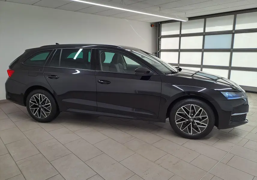 Vue de profil côté gauche d'une Skoda Octavia Combi 2025 noire Magic nacré avec jantes alliage 17'' Slagard Aero noir polies.