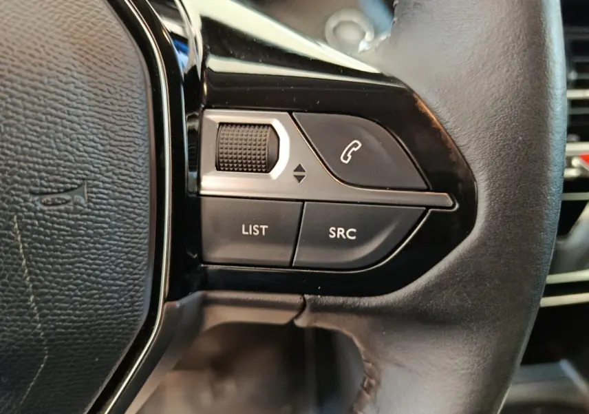 Gros plan sur les commandes gauche du volant cuir noir de la Peugeot 208 BlueHDi 100 S&S Allure Business 2020.