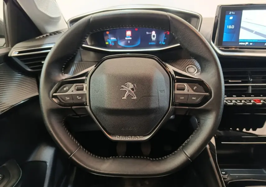 Vue rapprochée du volant cuir noir multifonctions d'une Peugeot 208 2020 avec tableau de bord numérique et écran tactile.