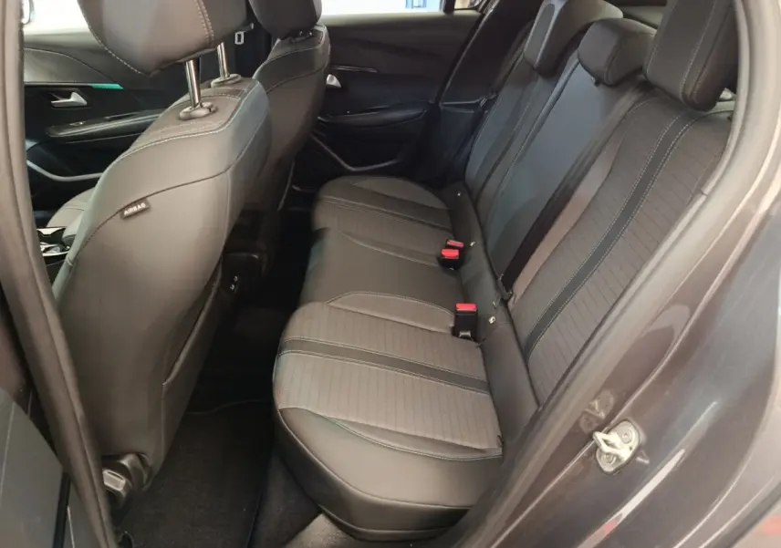 Vue côté droit des sièges arrière noirs en tissu et cuir dans une Peugeot 208 2020, porte ouverte.