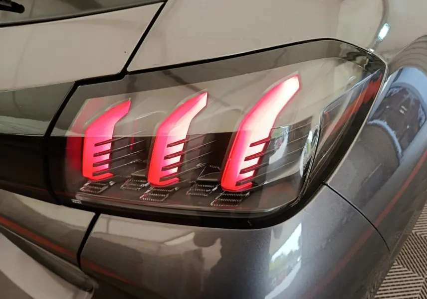 Gros plan sur le feu arrière droit rouge et noir d’une Peugeot 208 gris métallisé, version 2020.