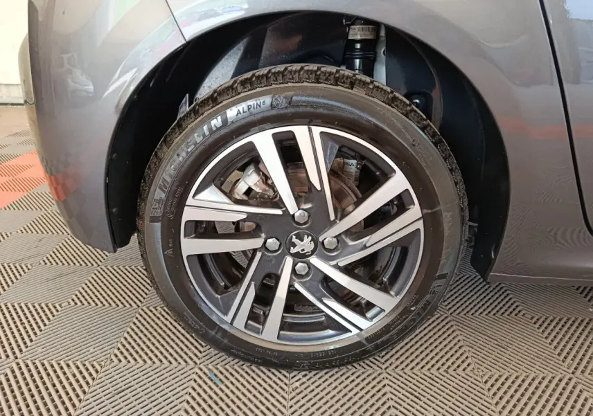 Gros plan sur la roue avant droite grise d'une Peugeot 208 avec jante alliage et pneu Michelin Alpin 6.