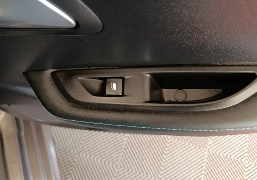 Gros plan sur la commande de lève-vitre côté conducteur de la Peugeot 208 BlueHDi 100 S&S Allure Business, intérieur noir.
