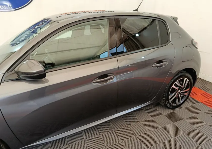 Profil droit d'une Peugeot 208 gris métallisé, mettant en valeur les jantes alliage et les rétroviseurs électriques.