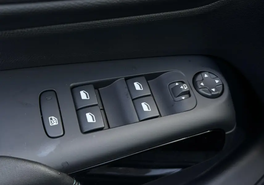 Gros plan sur les commandes de lève-vitres et réglages des rétroviseurs côté gauche d'un Citroën C5 Aircross Bleu Eclipse.