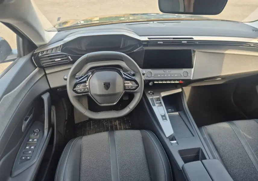 Vue intérieure avant de la Peugeot 308 noire 2025, avec volant multifonction et écran tactile central.