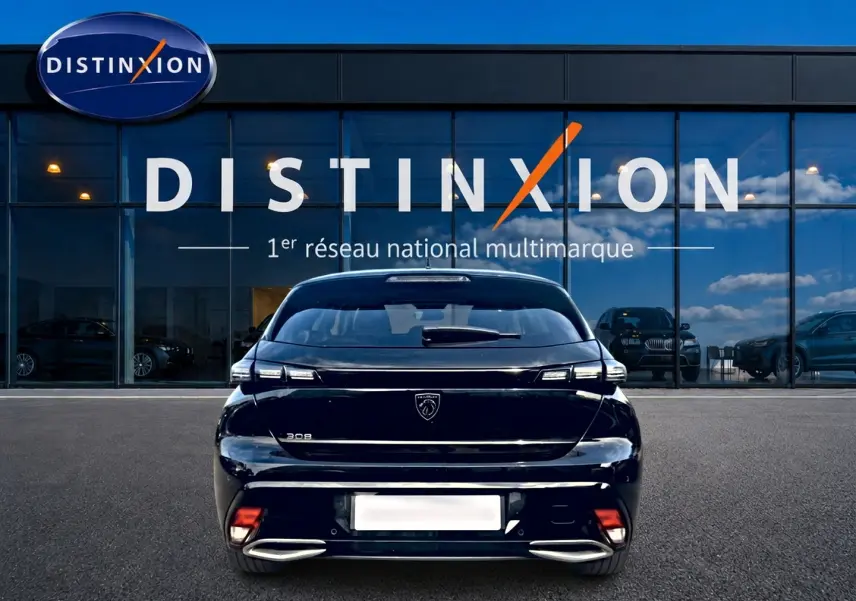Vue arrière d'une Peugeot 308 noire 2025 garée devant une vitrine avec logo Distinxion visible en arrière-plan.