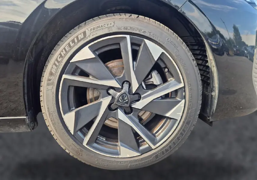 Gros plan sur la jante alu noire et grise de la roue avant droite d'une Peugeot 308 noire 2025.