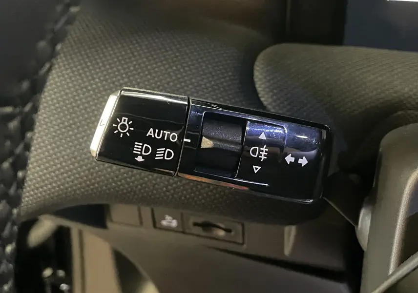 Bouton d'ouverture du coffre avec symbole de voiture sur panneau intérieur noir texturé, détail du Citroën C5 Aircross hybride.