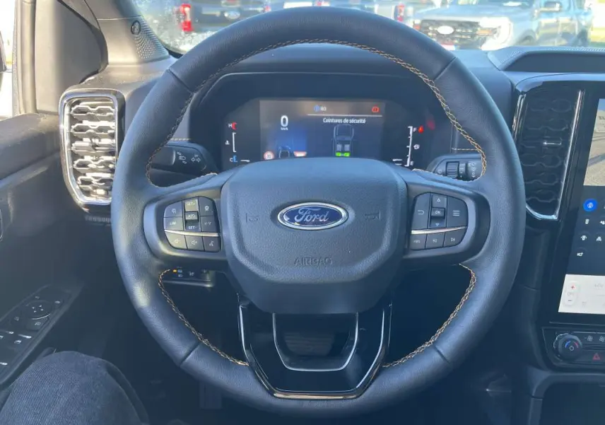 Vue centrée sur le volant cuir noir du Ford Ranger 2026 avec coutures marron et tableau de bord numérique.