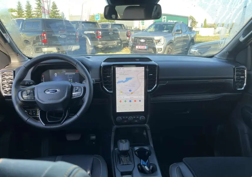 Vue intérieure frontale du Ford Ranger 2026 avec tableau de bord noir et écran tactile vertical central allumé.