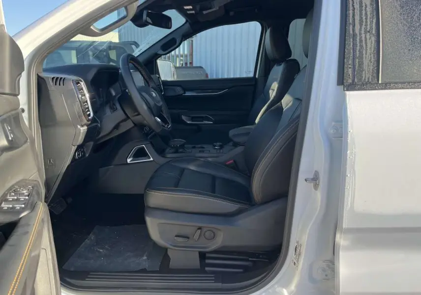 Vue intérieure côté conducteur du Ford Ranger blanc glacier 2026, sièges cuir noirs avec surpiqûres contrastées.