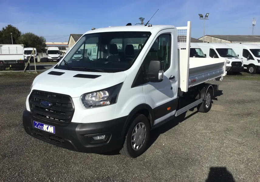Ford Transit Chassis Cabine blanc vu en 3/4 avant droit avec benne et bras polybenne sur parking extérieur.