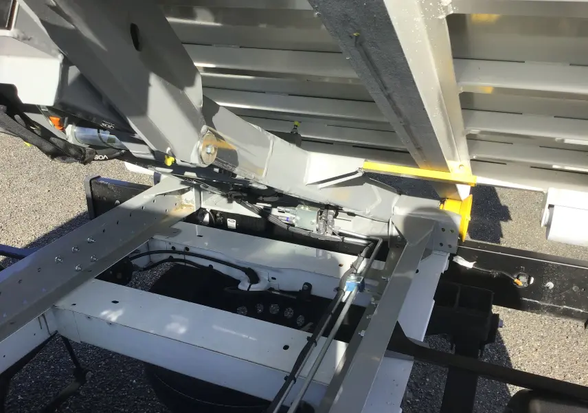 Gros plan sous la benne relevée du Ford Transit Châssis Cabine blanc, montrant le bras Polybenne et la structure métallique.