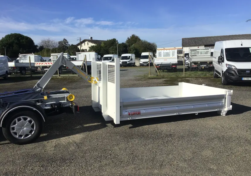 Vue latérale droite du châssis cabine Ford Transit blanc avec bras polybenne et benne 3m20 posée au sol.