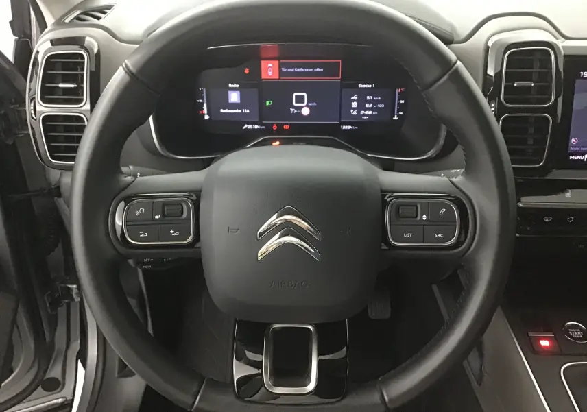 Vue rapprochée du volant cuir noir et du tableau de bord numérique du Citroën C5 Aircross gris Artense 2021.
