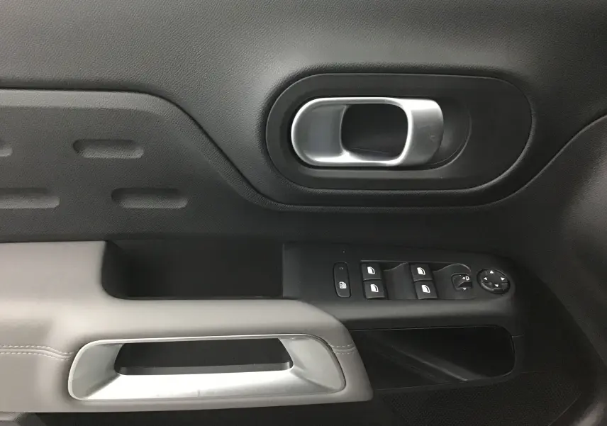 Poignée intérieure et commandes des vitres côté gauche d'une Citroën C5 Aircross gris Artense, finition Feel Pack 2021.