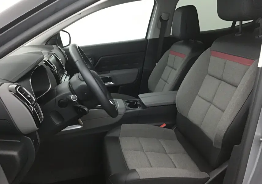 Intérieur avant droit du Citroën C5 Aircross gris, sièges tissu gris avec bande rouge et volant cuir noir.
