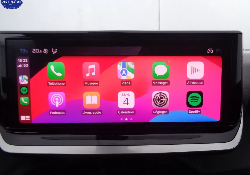 Écran tactile central de la Peugeot 2008 2023 affichant Apple CarPlay avec icônes colorées sur fond rouge et violet.