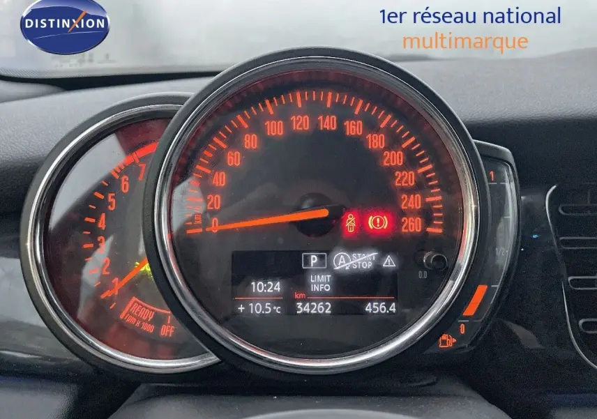 Gros plan sur le tableau de bord de la MINI Cabriolet rouge Chili, affichant le compteur de vitesse et les voyants allumés.
