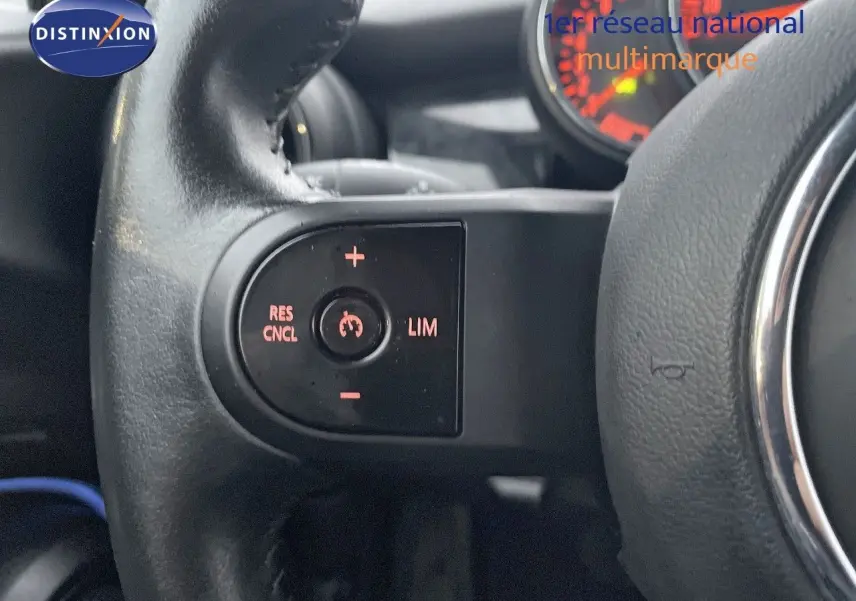 Gros plan sur les commandes de régulateur de vitesse au volant d’une MINI Cabriolet F57 rouge chili, intérieur noir.