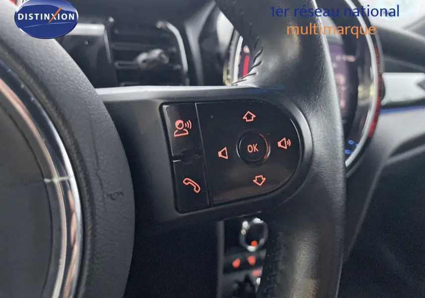 Gros plan sur les commandes du volant de la MINI Cabriolet F57 rouge chili, avec éclairage orange des boutons.